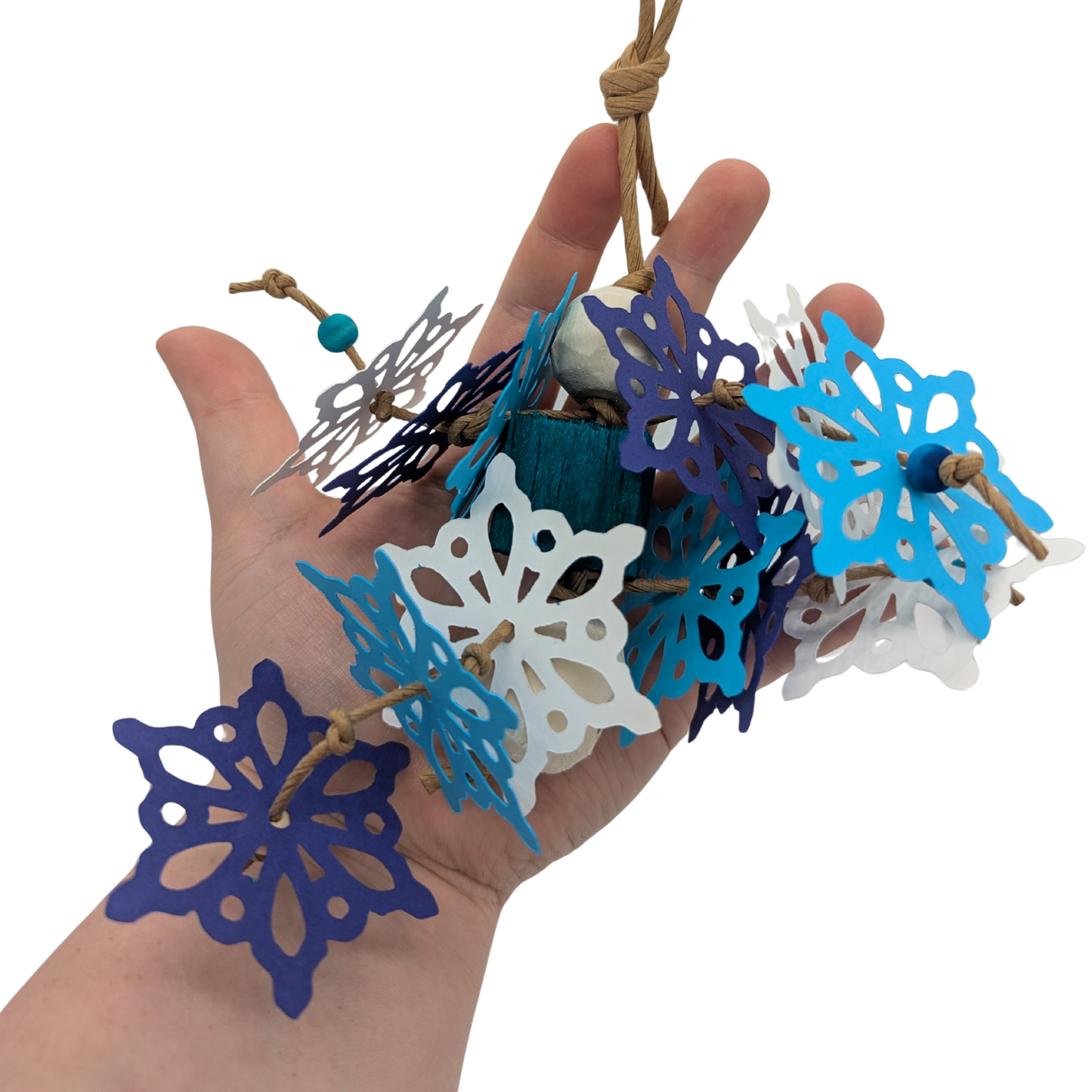 Hand holding a bird toy with blue and white snowflakes.