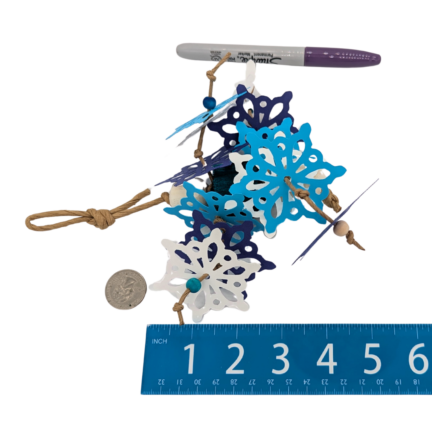 Bird toy with blue and white snowflakes, on a white background with a ruler and a pen for scale.