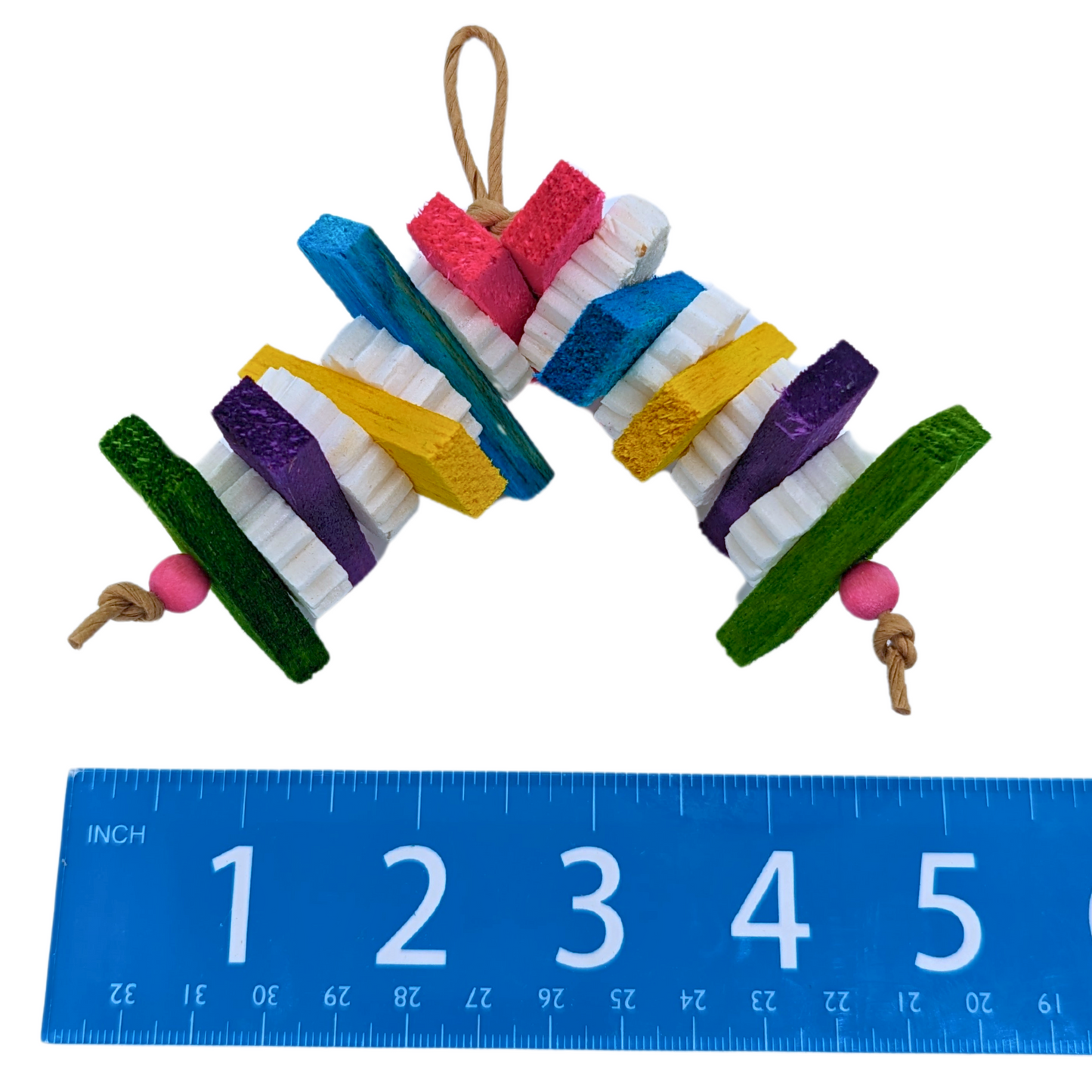 A small bird toy made with colorful balsa slats and separated by sola discs. Next to a ruler for scale.