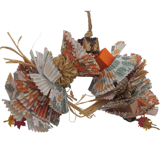 A colorful bird toy made of mahogany pods, cupcake papers, and other natural materials designed to resemble decaying leaves.