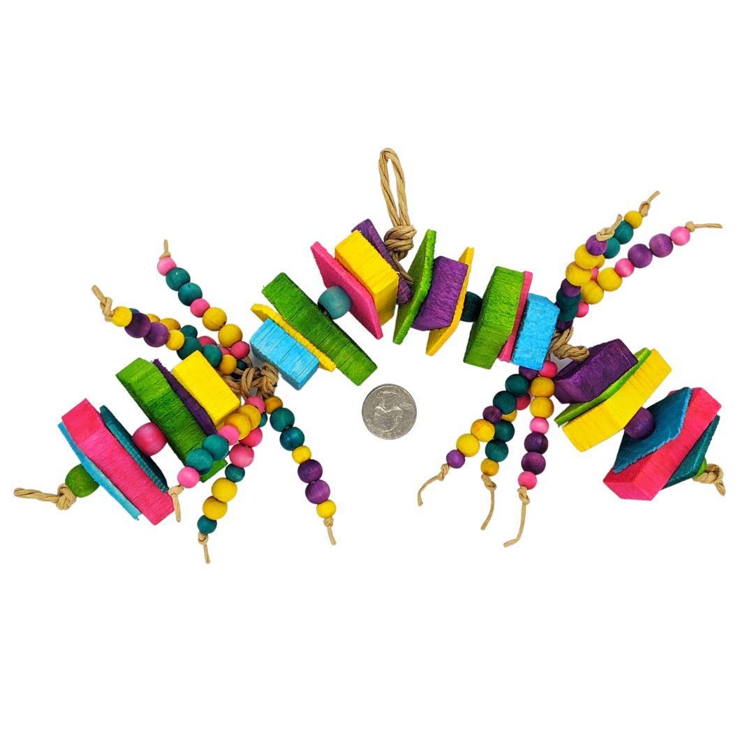 A brightly colored parrot toy. Has alternating sections of 1/8 thin pine with 1/2 inch balsa slats, separated by 1/2 inch wooden barrel beads. In the middle of the toy are two sections of 6 strands each of 8mm and 10mm wooden beads. Next to a quarter.