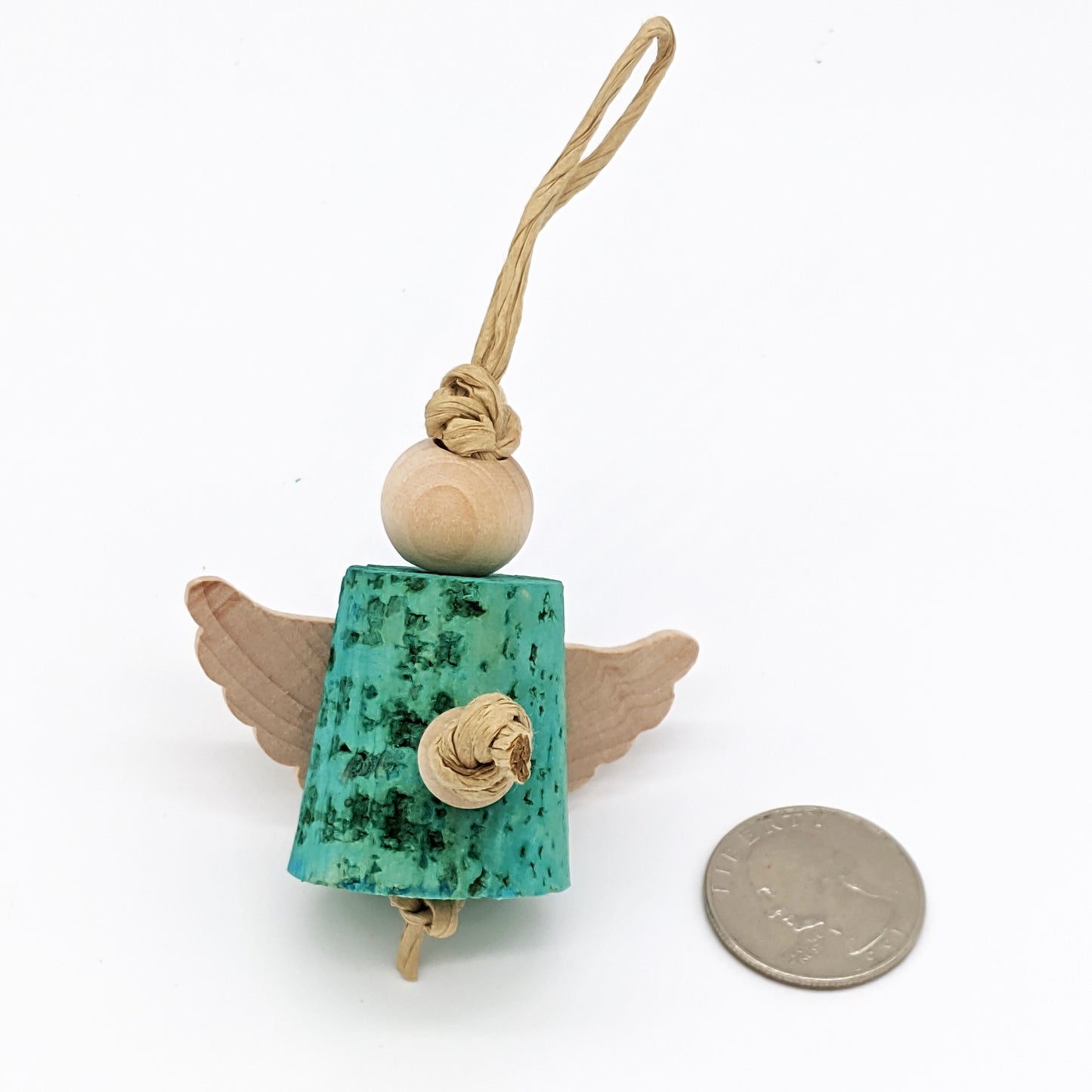 A small bird toy that looks like an angel next to a US quarter for scale