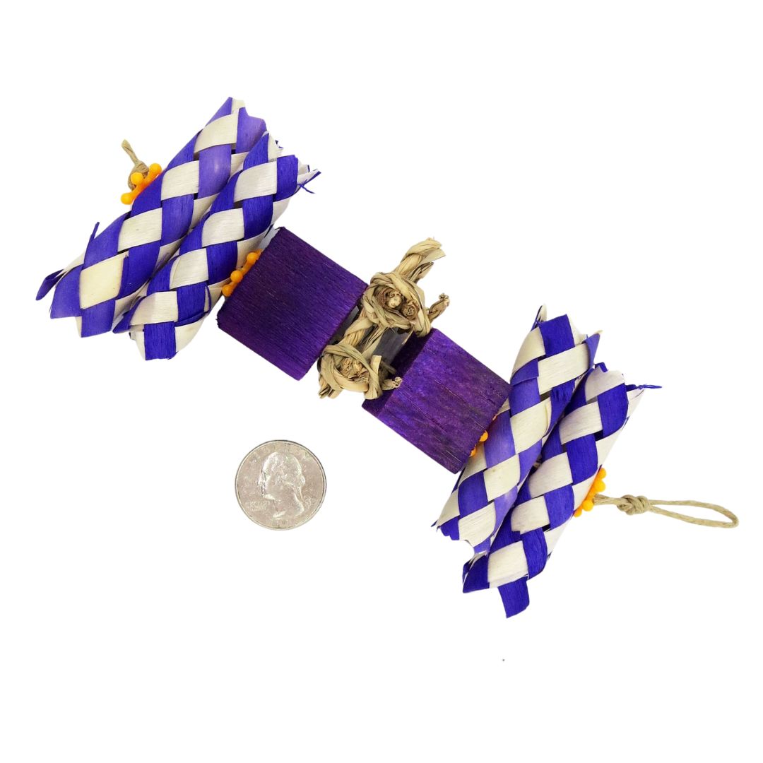 Bird toy with palm finger traps cut in half, two balsa blocks, and a piece of seagrass in the center. Purple coloration. Shown next to a quarter for scale