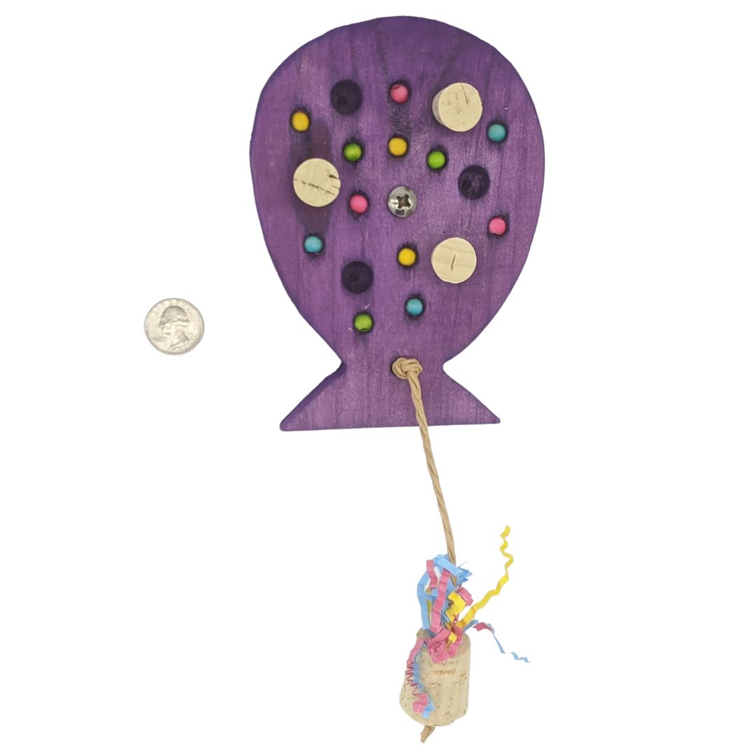 A birthday balloon shaped piece of pine, with embedded corks, wooden beads, and string with cork weight. Shown next to US quarter for scale