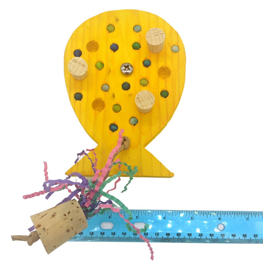 A birthday balloon shaped piece of pine, with embedded corks, wooden beads, and string with cork weight.