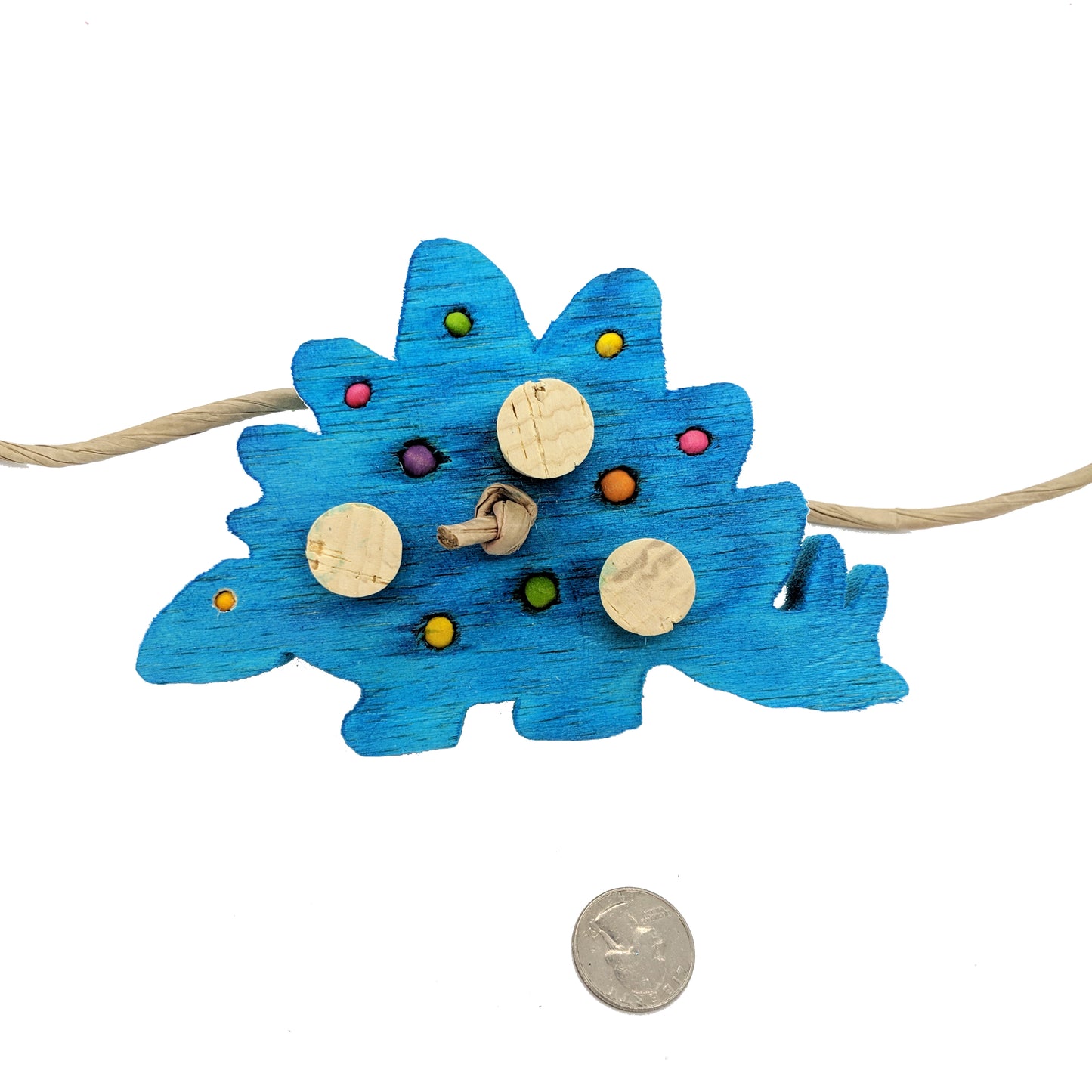 A stegosaurus shaped piece of balsa. Embedded with 4mm, 6mm, and 8mm wooden beads, and three cork stoppers. Shown with ruler at 6 inches wide.
