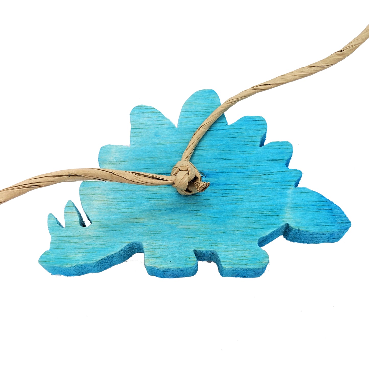 A stegosaurus shaped piece of balsa. Showing the back of the toy with paper rope that is used to secure the toy to the cage side.