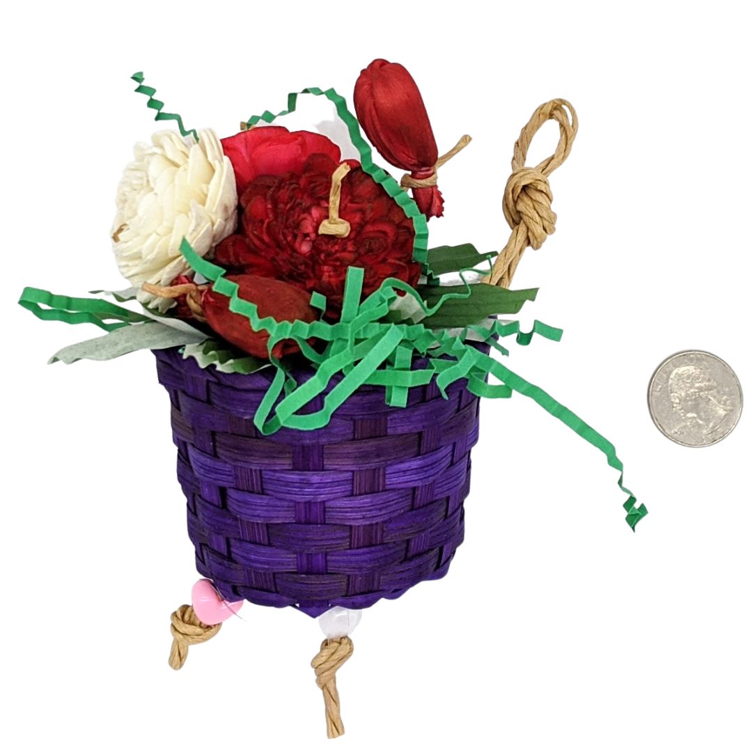 A bird toy with a basket, overflowing with 3 sola flowers dyed red, white, and pink. With shred paper and cupcake liners.