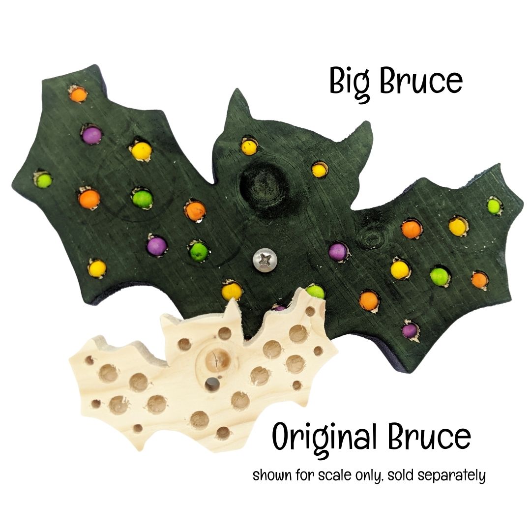 A bat shaped piece of pine with embedded beads and/or millet. Shown with the smaller bat toy for scale