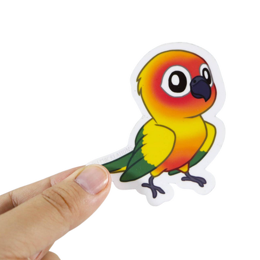 Sun Conure Vinyl Sticker by Emii Creations, held between fingers to show scale
