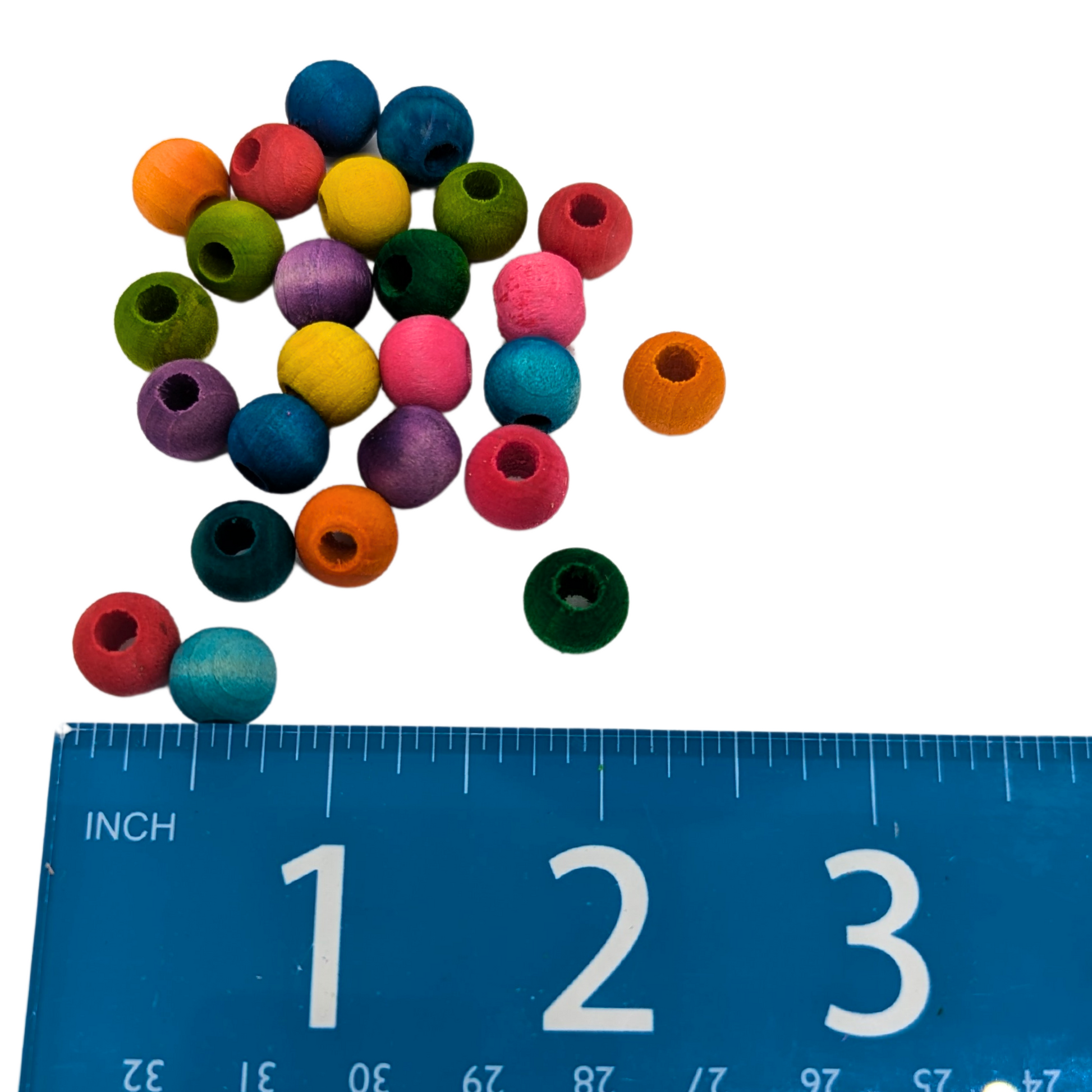 A set of 25 multicolored wood beads measuring 10mm, by Lil Monsters Bird Toys, shown next to a ruler for scale