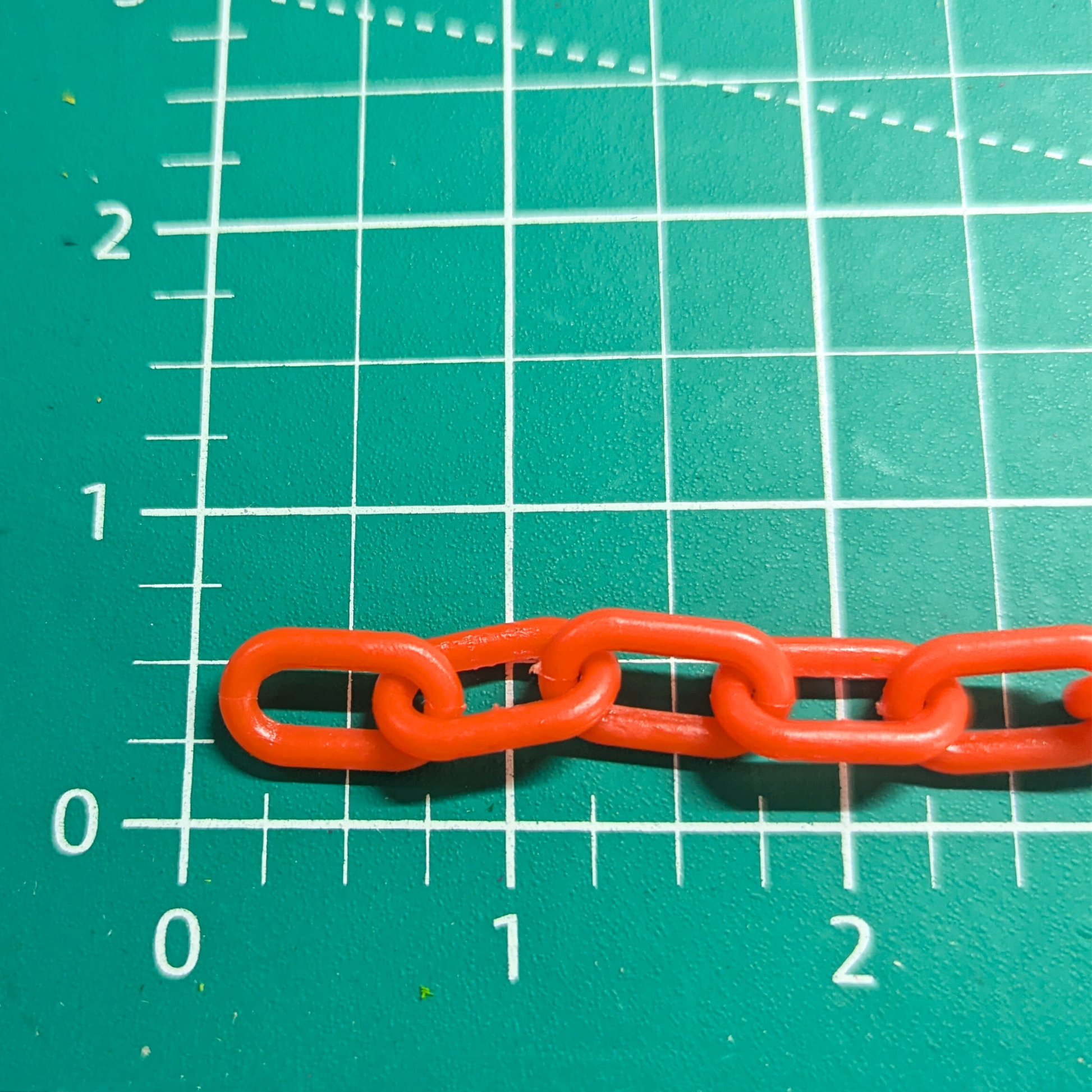 3mm orange plastic chain shown on measurement mat for scale, close up