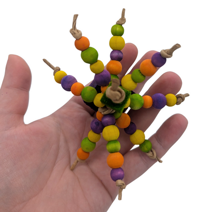 Colorful beaded bird toy held in a hand against a white background