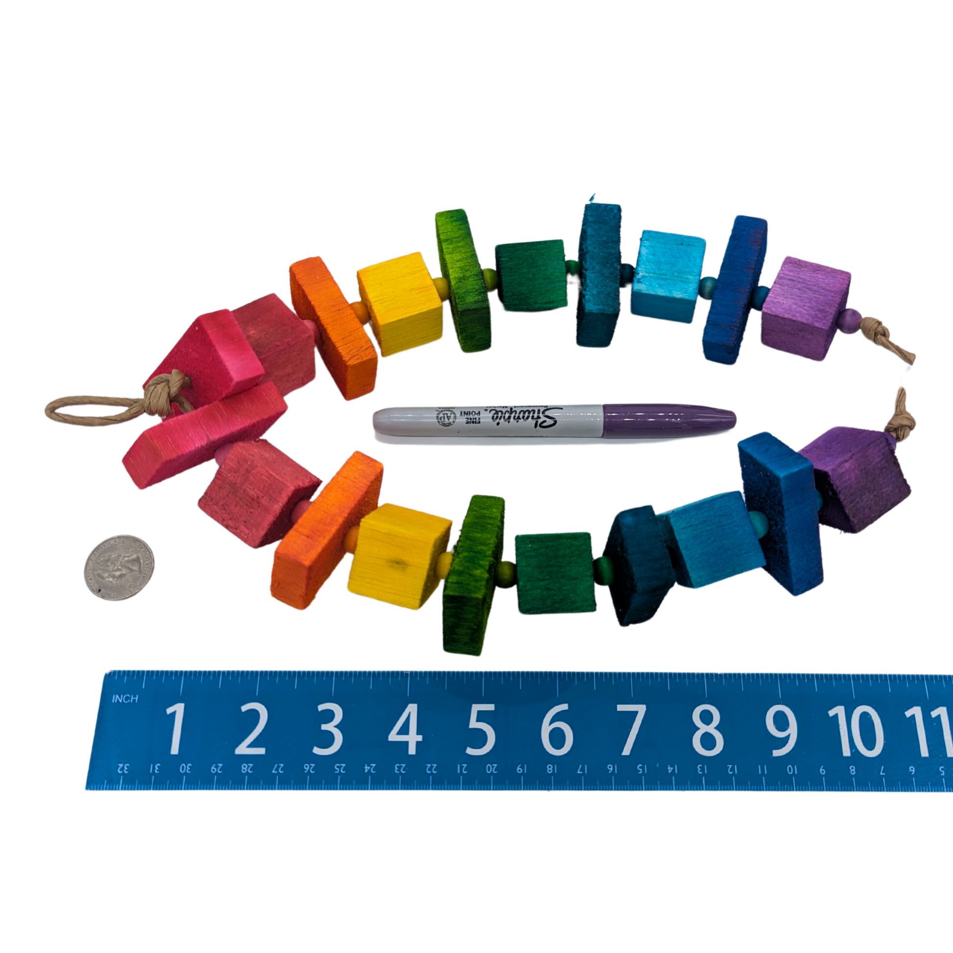 Balsa Rainbow Bird toy, shown next to a ruler, quarter, and permanent marker for scale. 