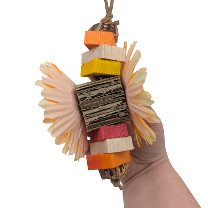 Hand holding a colorful bird toy with various materials on a white background