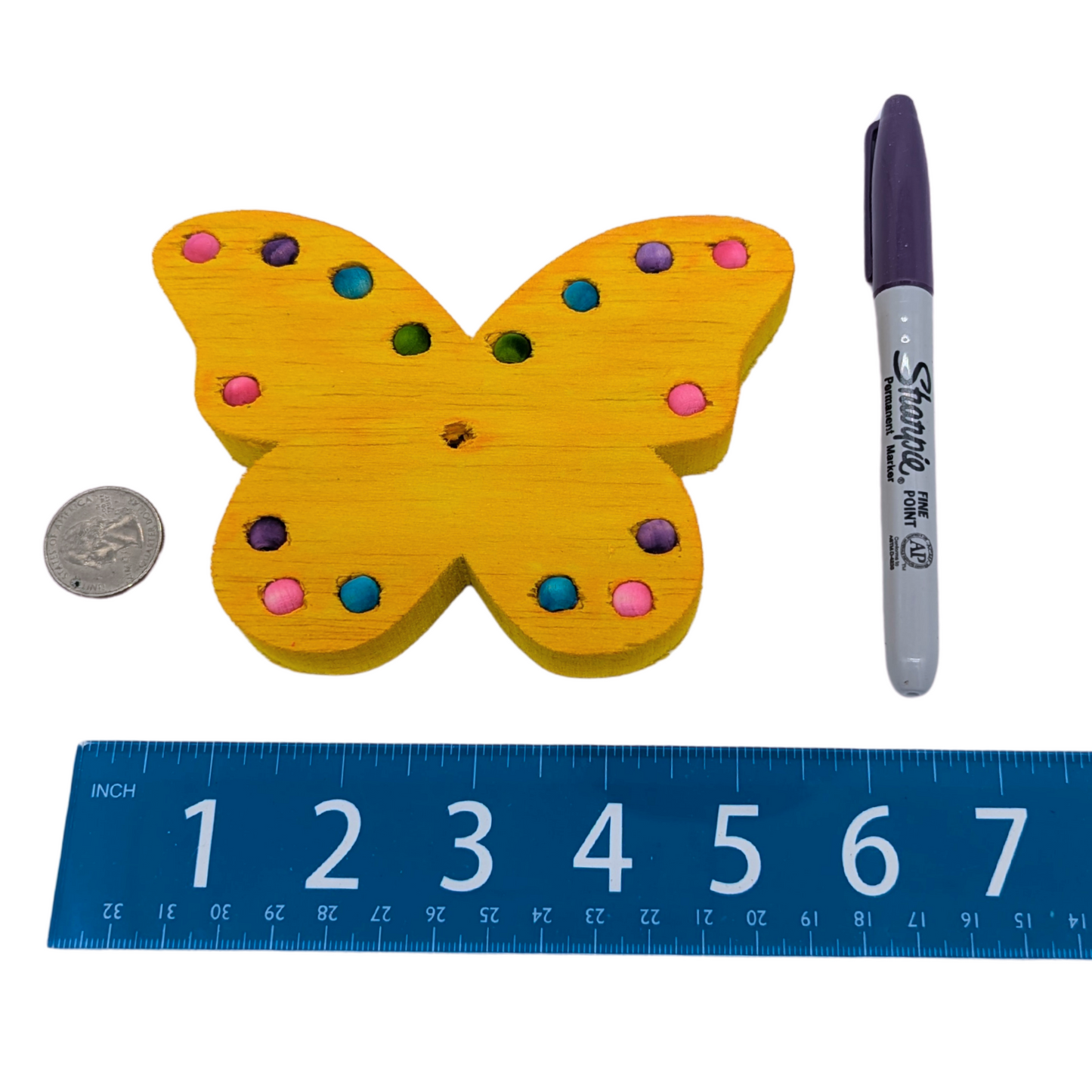 Flutterby balsa bird toy by Lil Monsters Bird Toys next to a sharpie, ruler, and US quarter for scale
