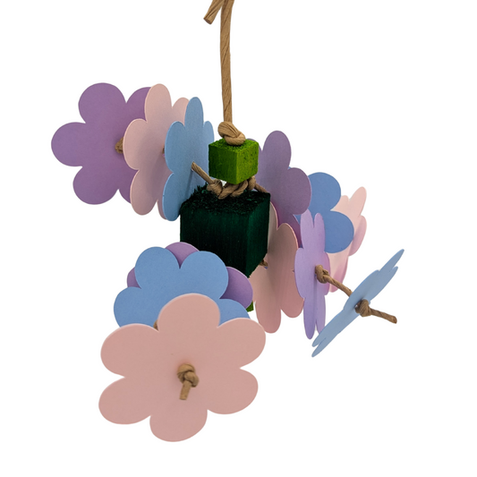 A bird toy made with pastel cardstock flowers and balsa blocks on a white background. 