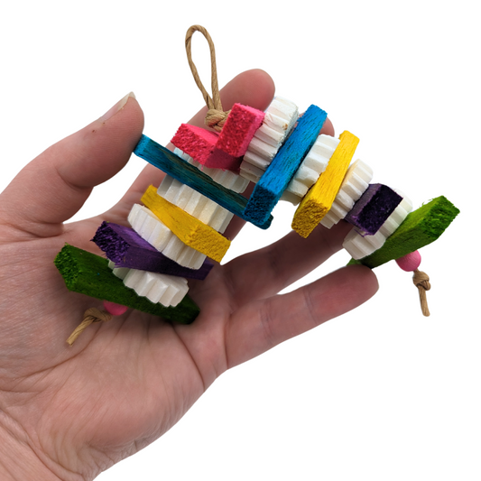 Teensy small bird toy made with colorful balsa slats and separated by sola discs. Held by a hand for scale. 
