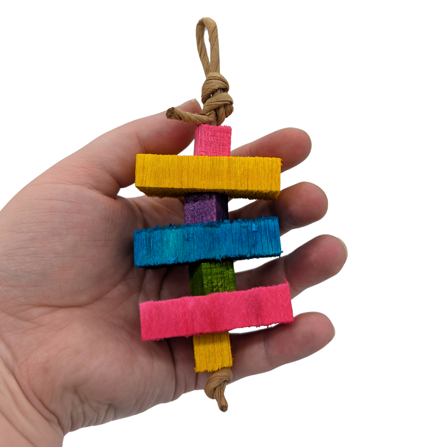 Colorful bird toy with wooden blocks and a rope held in a hand on a white background