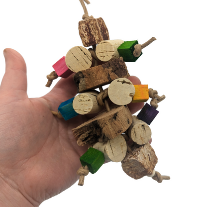 Corky parrot toy by Lil Monsters Bird Toys, with cork stoppers, cork bark, balsa, and mahogany pods, in hand for scale
