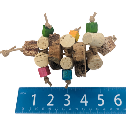 Corky parrot toy by Lil Monsters Bird Toys, with cork stoppers, cork bark, balsa, and mahogany pods, next to ruler for scale