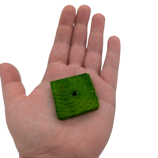 Quarter inch pine slices bird toy by Lil Monsters Bird Toys, one held in hand for scale
