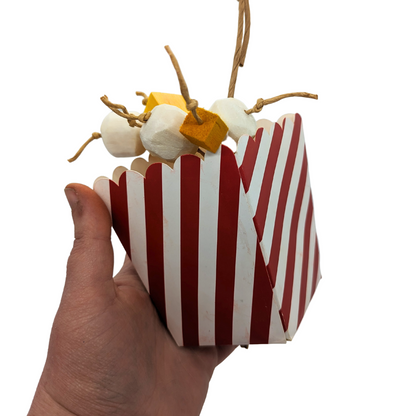 Snack Attack popcorn themed parrot toy by Lil Monsters Bird Toys, held in hand for scale