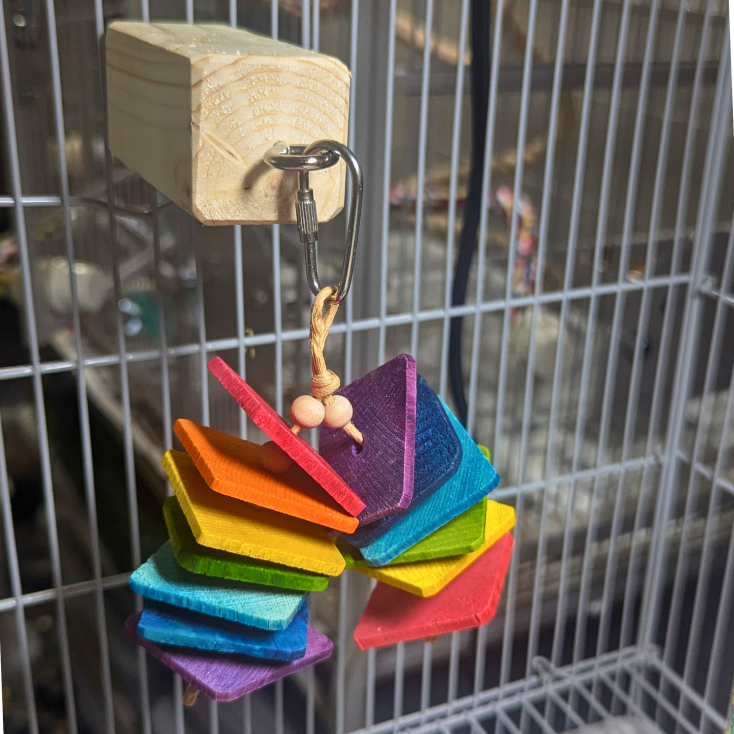 Toy Helper perch by Lil Monsters Bird Toys, shown in use on a cage with another toy hanging off of the eyehook