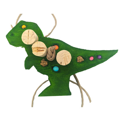 Balsasaurus Rex by Lil Monsters Bird Toys. A piece of balsa cut into the shape of a t-rex dinosaur. Embedded with cork stoppers, beads, and millet. Shown in a green color. 