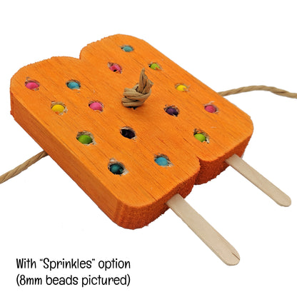 A twin popsicle shaped piece of balsa with popsicle sticks coming out the bottom, and paper rope through the middle. With embedded beads