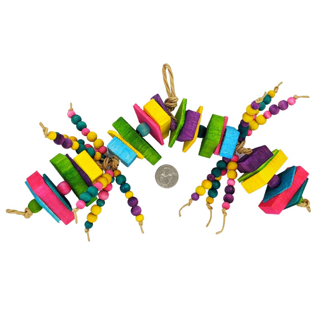 A brightly colored parrot toy. Has alternating sections of 1/8 thin pine with 1/2 inch balsa slats, separated by 1/2 inch wooden barrel beads. In the middle of the toy are two sections of 6 strands each of 8mm and 10mm wooden beads. Next to a quarter. 