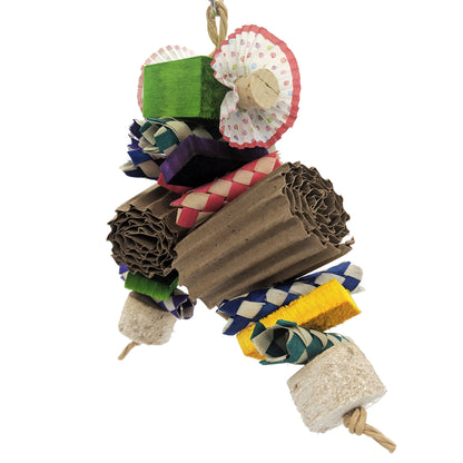 A parrot toy, with a 2 x 2 x 1 inch balsa block at the top. embedded with 2 cork stoppers and cupcake liners. From there on two strands, palm finger traps, half inch balsa slats, rolled corrugated cardboard, and finished with yucca chunks. 