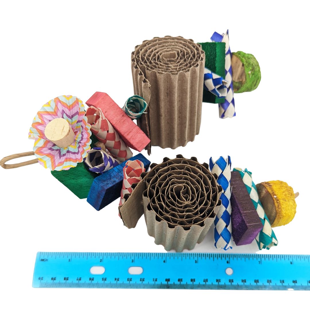 A parrot toy, with a 2 x 2 x 1 inch balsa block at the top. embedded with 2 cork stoppers and cupcake liners. From there on two strands, palm finger traps, half inch balsa slats, rolled corrugated cardboard, and finished with yucca chunks. Shown with Ruler