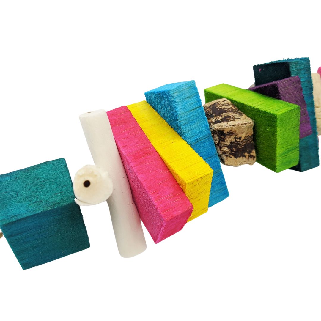 Close up of parrot toy. One inch balsa cube, thin sola sticks, half inch balsa slats, and mahogany pod slice.
