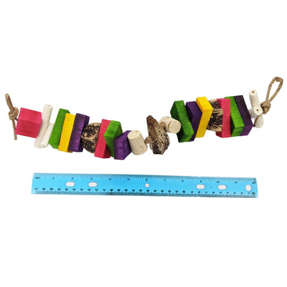 A toy for parrots that hangs from both ends as a garland. Features 1 inch balsa blocks, cork stoppers, mahogany pod slices, sola sticks, and half inch thick balsa slats. In the center is a whole mahogany pod. Shown with 12 inch ruler for scale.